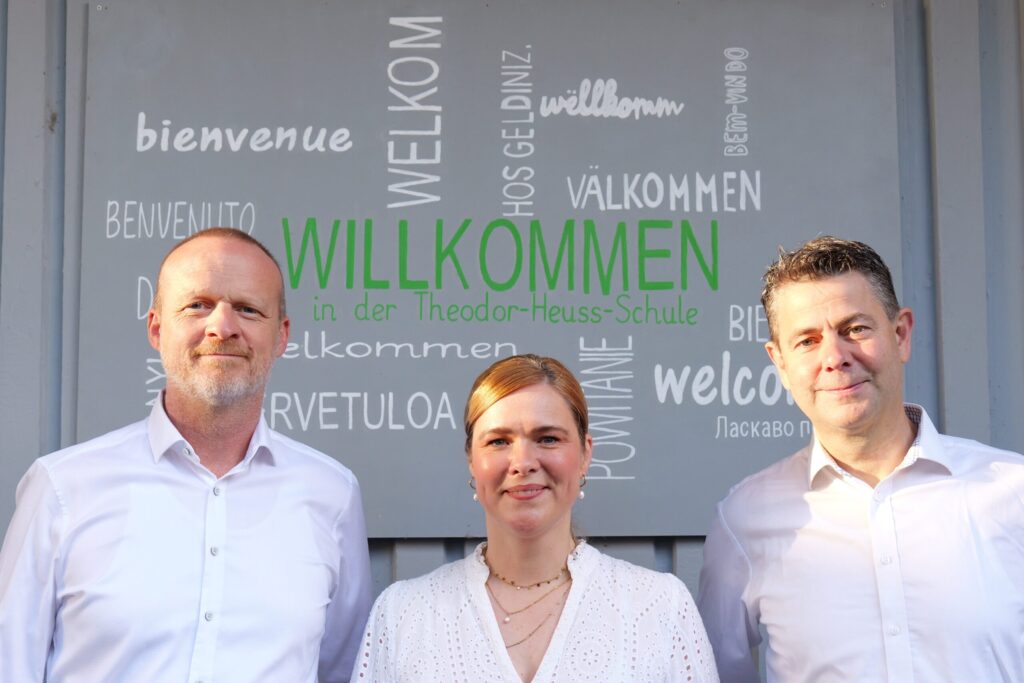 Gruppenfoto Schulleitung vor der Begrüßungstafel
